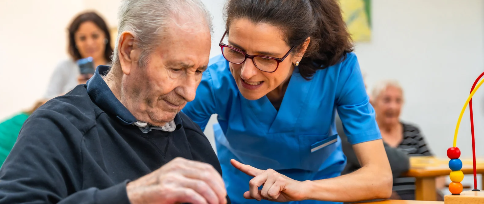 Senior working on a puzzle with aide assistance at a memory care community
